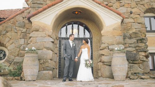 Bride and groom in front of door at Mt. Woodson Castle. 