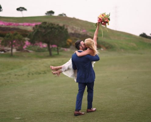 Crossings at Carlsbad wedding bride hold bouquet in the air on golf course