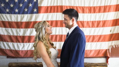 bride and groom in front of american flag