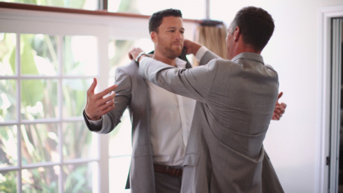 Groomsmen help each other put on suit before wedding