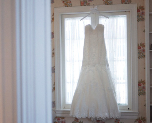 Wedding dress hanging in front of the window.