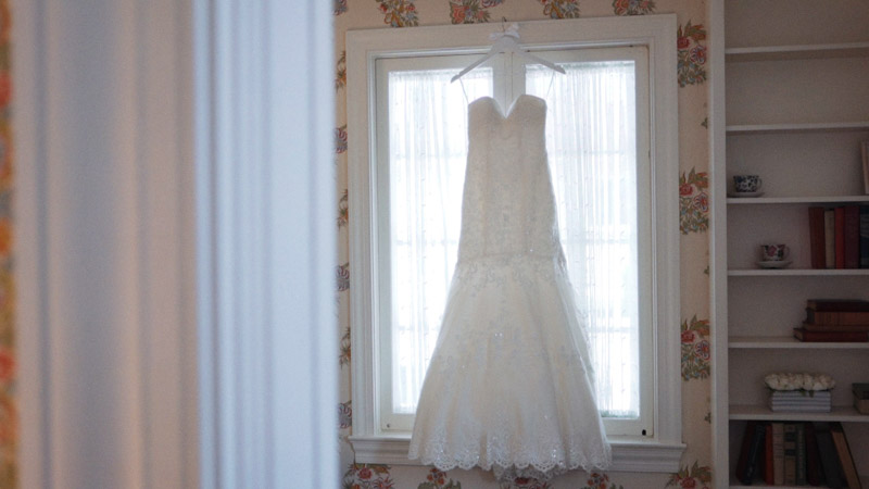 Wedding dress hanging in front of the window.