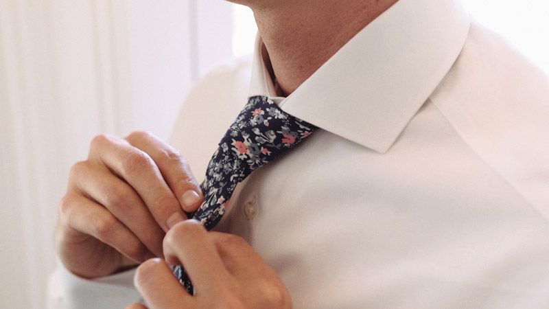 Groom fixes his tie before wedding