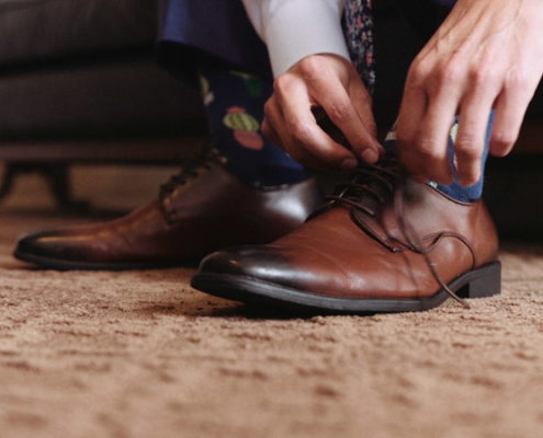Groom tying his shoes before wedding