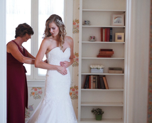 Mom helps bride lace up wedding dress