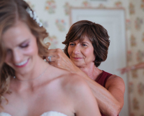 Mom helps bride put on necklace before wedding ceremony