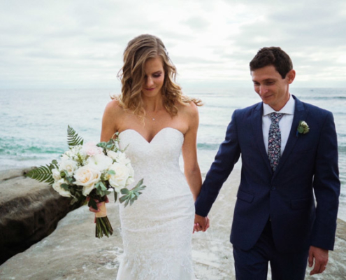 Bride and groom hold hands on beach in La Jolla Cove Wedding Video