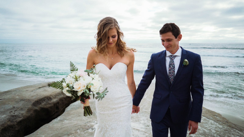 Bride and groom hold hands on beach in La Jolla Cove Wedding Video