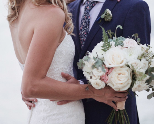 Bride and groom on beach with bouquet