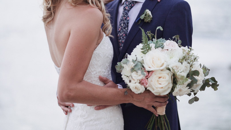 Bride and groom on beach with bouquet