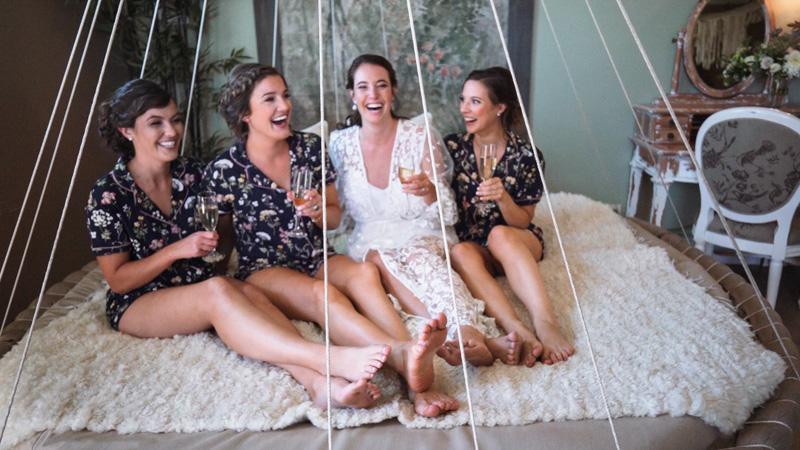 Bridesmaids and bride on drink champagne and laugh on bed