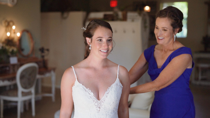 Mom helps bride get into wedding dress
