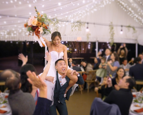 Groom carries bride into wedding reception on his shoulders