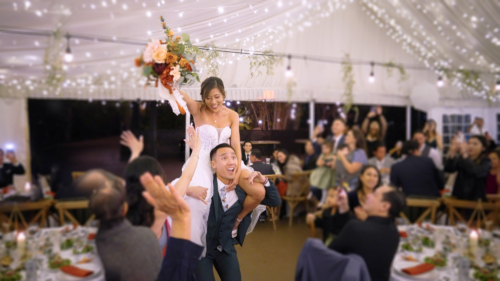Groom carries bride into wedding reception on his shoulders
